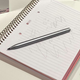 The MSI Pen 2 stylus sitting on a paper notebook with a page covered in scribbles.